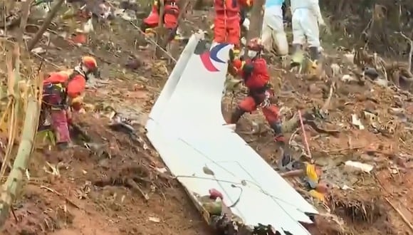Los equipos de rescate con una pieza del fuselaje mientras continúan su búsqueda en el lugar donde un avión de pasajeros de China Eastern se estrelló contra la ladera de una montaña cerca de Ciudad de Wuzhou en la región sur de Guangxi en China.. (Foto: various sources / AFP)