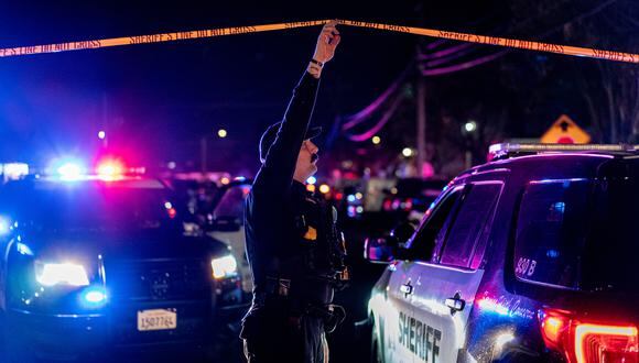 Un oficial del Departamento del Sheriff del condado de Sacramento sostiene una cinta policial para permitir que un vehículo ingrese a la escena del crimen. (Foto: Andri Tambunan / AFP)