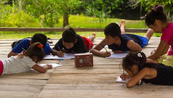 Menores estudiando con una radio en el medio. (Foto: Vatican News)