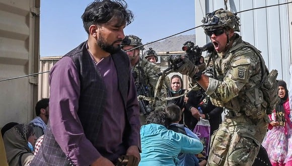 Un soldado estadounidense apunta con su arma hacia un pasajero afgano en el aeropuerto de Kabul el 16 de agosto de 2021. (Wakil KOHSAR / AFP).