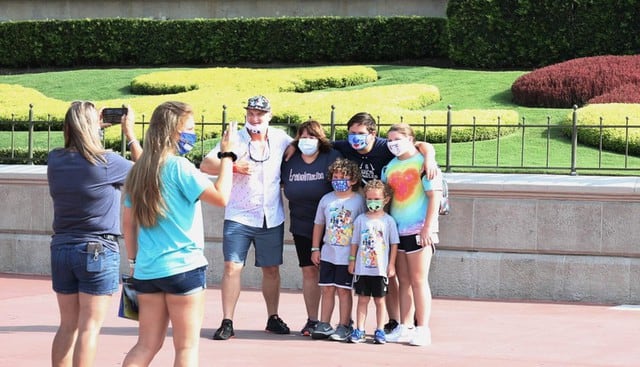 Los invitados se toman fotos de recuerdo en la entrada del parque temático Magic Kingdom en Walt Disney World (Florida). (AFP / Gregg Newton).